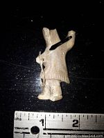 Front view of the carved Eskimo hunter pin showing the detailed figure, size reference with ruler