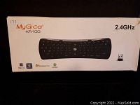 Box front showing MyGica KR100 wireless mini keyboard image with specs and system compatibility icons.