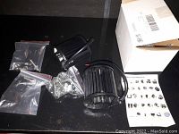 Two black LED light bars with heat sink fins, wiring, and mounting hardware on black surface