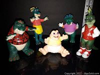 Group photo of five Dinosaurs TV show action figures on a black reflective surface
