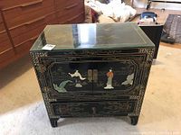 Angled front view showing double doors with carved figures, painted gold detailing and brass hardware