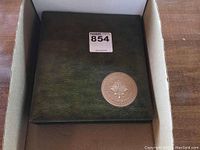 Closed green binder with maple leaf medallion on cover