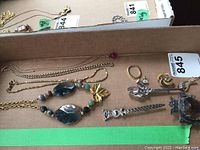 Photos of assorted Celtic-themed jewellery items including gold-coloured necklaces, a stone bead necklace with gold leaf pendant, and several brooches and pins with intricate metallic designs.