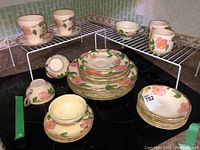 Wide view showing entire dish set including plates stacked in center and cups and mugs arranged around