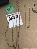 Three gold chains on cardboard with '10K' label, including a rope chain on left and a thin chain in center
