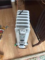 Front angle view of white Honeywell oil-filled radiator heater showing fins, caster wheels, power cord, and model tag sticker.