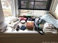 Overview of all lot contents including jewelry bags, box, purse, scarves, watches, and cosmetic containers on window ledge