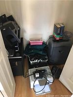 Photo of corner with large black shredding machine, HP printer beneath, and basket with cords and cables, filing cabinet, and phones
