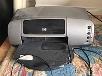 HP Photosmart 7150 printer with front tray open, resting on carpet.