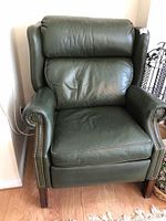 Front view of green leather recliner with wingback design and studded arm trim
