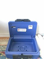 Open blue Sentry Safe lockbox showing hollow interior with small shaped indentations on the base.