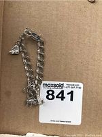 Sterling silver chain-link bracelet with three animal charms: bear, elephant, rabbit, shown laid out on a cardboard surface.