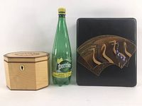 Side view of wooden octagonal box next to black square Japanese-style box and Perrier bottle for scale.