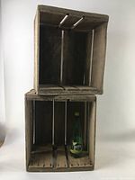 Two stacked weathered wood crates with a green Perrier bottle for scale, showing interior and exterior condition.