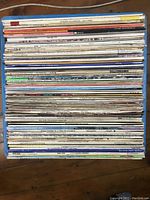 Top view of a stack of vinyl LP records focusing on the spines showing artist names and album titles.
