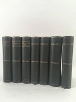 Front view of seven vintage George Eliot books standing upright showing spines with gold embossed titles and author name.