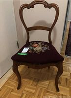 Front view of the parlour chair showing wooden frame and needle point floral seat upholstery.