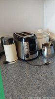 Photo of Black+Decker C8G100SC stainless steel coffee grinder with black top and power cord on a gray kitchen counter