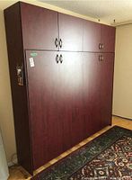 Front view of closed cherry-finish wall bed cabinet with six cabinet doors and metal handles