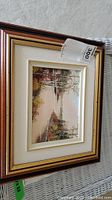 Framed original painting showing a stream scene with trees and water reflections, with visible price tag of $300 on the upper right corner.