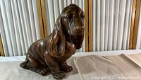 Front view of seated basset hound plaster statue showing detailed ears and face.
