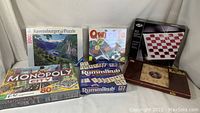 Front view of collection showing Ravensburger puzzle, Qwirkle, Rummikub, Monopoly, magnetic Checkers, and Kalaha games