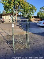 Straight view of green metal 3 tier plant stand with flower and leaf detail.