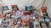 Photo showing a wide assortment of cross stitch kits, beading kits, multiple small packets of beads and jewelry findings, and a soap making kit box.