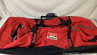 Side view of the large red Marlboro duffle bag with black base and black handles with Marlboro branding