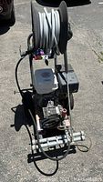 Full view of the Power Ease gasoline commercial pressure washer showing hose reel and gasoline engine mounted on a metal frame.