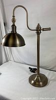 Full side view of Victorian style brass finish dome shade table lamp with adjustable neck showing lamp base and cord.