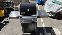 Full front view of Weber Spirit propane barbeque grill with stainless steel side shelves extended.