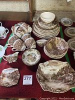 Full view of the dinnerware set arranged on a surface showing stack of plates, bowls, cups, saucers, and a serving piece all decorated with Old English Countryside pattern