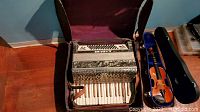 Full view of S. Marino accordion inside a tattered case with visible white piano keys and button panel.
