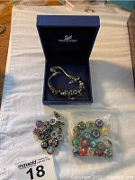Charm bracelet displayed inside blue Swarovski box with bag of loose beads