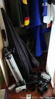 View of tripod, photography umbrella, Sony camera with attached lens, and two additional cameras.