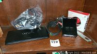 Sony VAIO laptop with power cables, Creative Zen Stone Plus box, and black strobe light on wooden shelf.