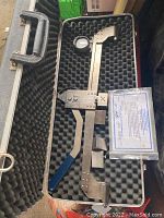Opened carrying case showing mechanical tensiometer with analog dial and instruction card inside foam padding.