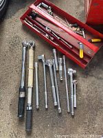 Photo of assorted socket wrenches and extensions placed next to a red toolbox (not included)