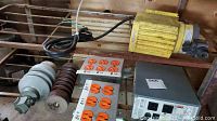 Overview of power supply unit, two ceramic insulators, and two power outlet strips arranged on a wood surface in a garage setting.