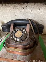 Front view of vintage rotary dial telephone with visible rotary dial, copper body and black handset