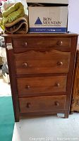 Front view of the vintage wooden secretary desk showing four drawers and wooden knob handles.