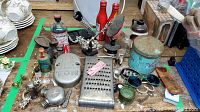 Overview of assorted vintage tools, bottles, metal weight and Coca-Cola tins arranged on a table