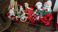 Full set of 14 Annalee Christmas dolls arranged mainly seated together, including Santa, Mrs. Claus, elves, mice, and sled.