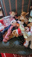 Photo showing multiple Beanie Babies piled on a chair including patriotic themed one featuring the American flag design, a kangaroo, holiday themed bears, and others.