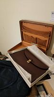 Brown leather envelope bag with gold clasp inside briefcase.