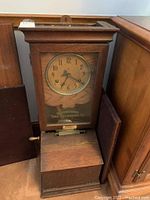 Full view of oak wooden time clock showing case, dial, lever, and lower card slot