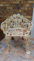Front view of vintage iron garden chair showing grape and vine design and paint wear
