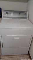 Full view of white front loading Kenmore dryer showing door and control panel area.