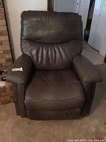 Full view of the brown faux leather recliner showing the seating, armrests, and overall chair design.